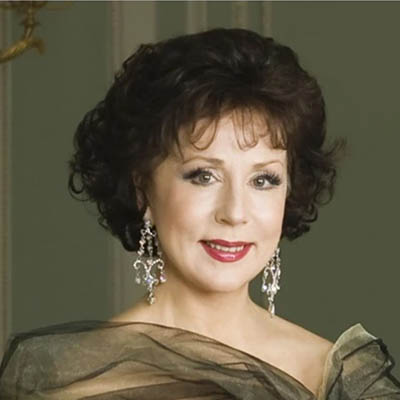 A woman with elegantly styled hair, large earrins, and dramatic makeup