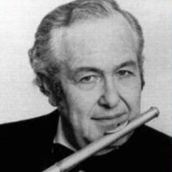 A man in a tuxedo holding a flute, ready to play music at a formal event