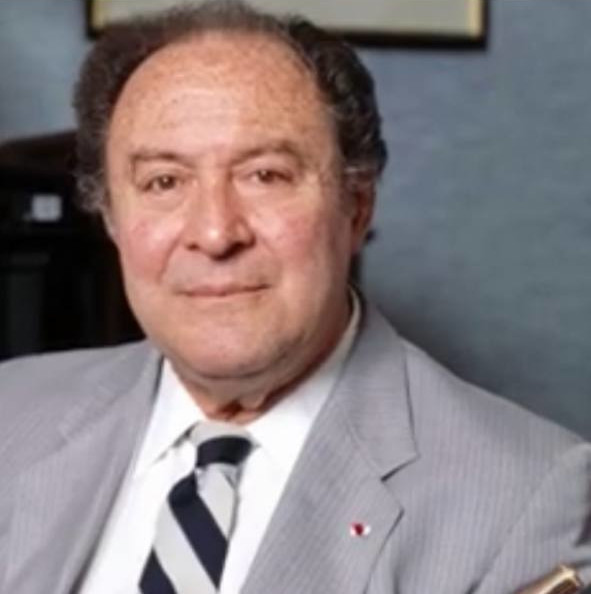 A man in a suit and tie, holding a flute