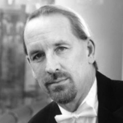 A well-dressed man in a tuxedo confidently gazes at the camera