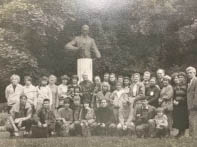 A group of people smiling and posing for a photo in front of a statue